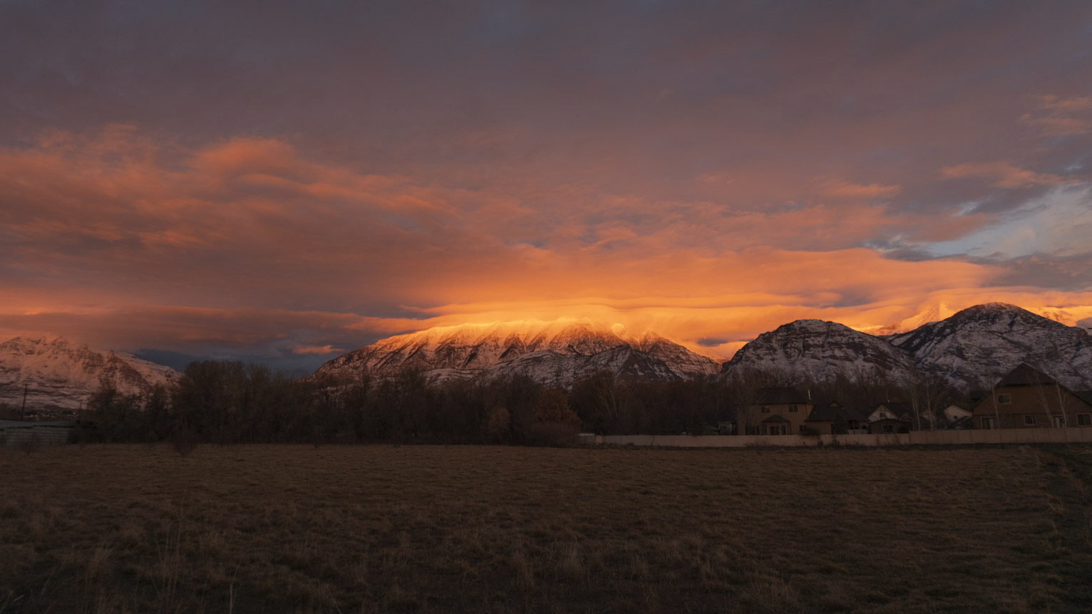 The mountains are bisected by clouds lit red in sunset